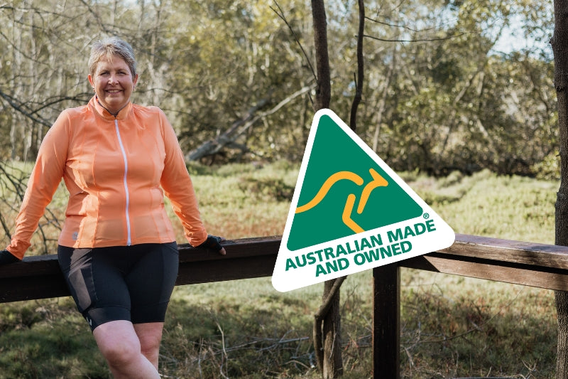 Cyclist leaning on fence in bush Australian made logo