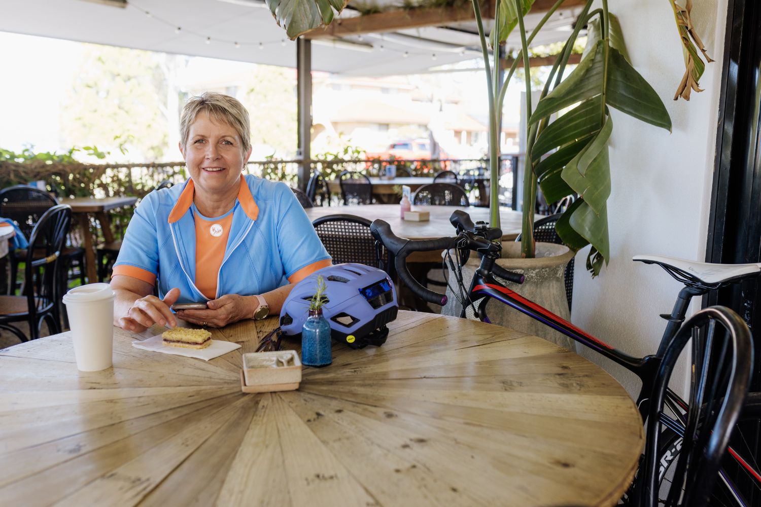 female cyclist in a blue jersey sitting at a coffee shop