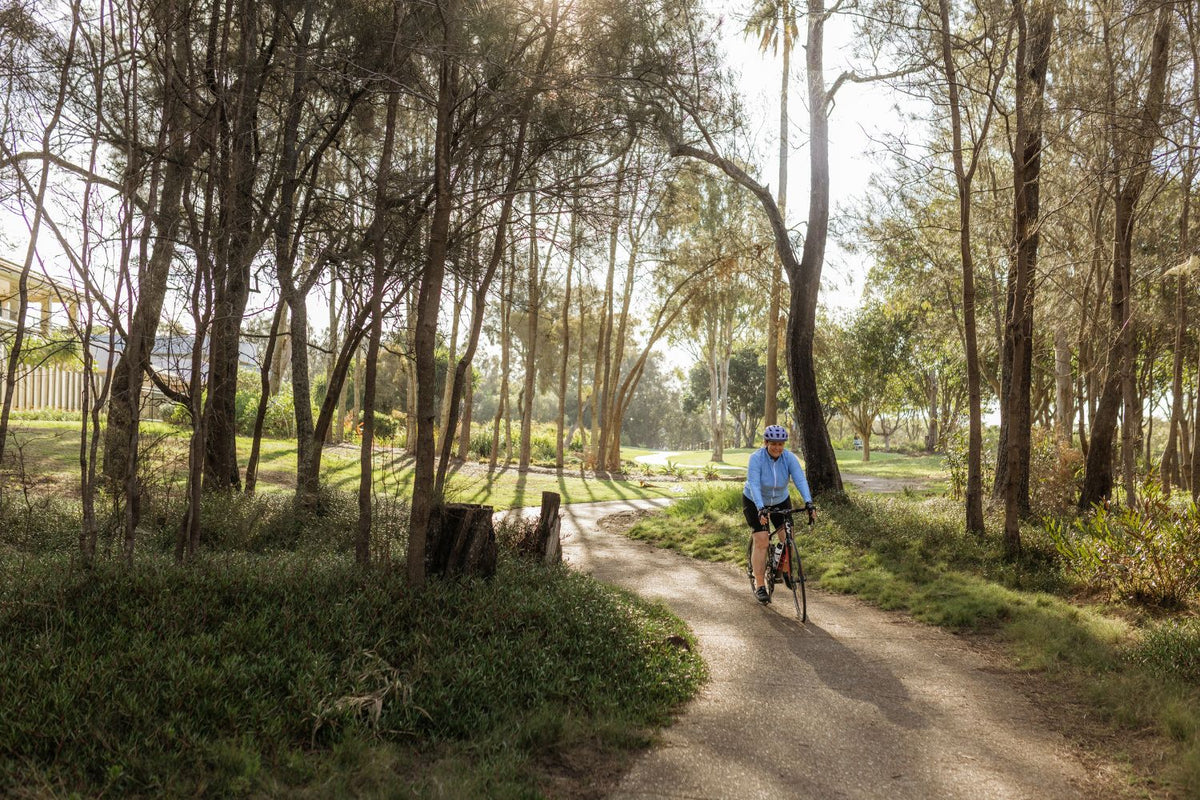 female cyclist riding along a tree lined path