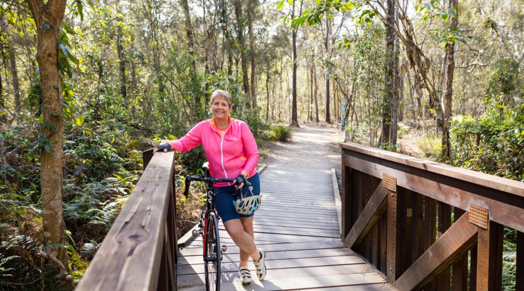 female cyclist on a bridge near her bike