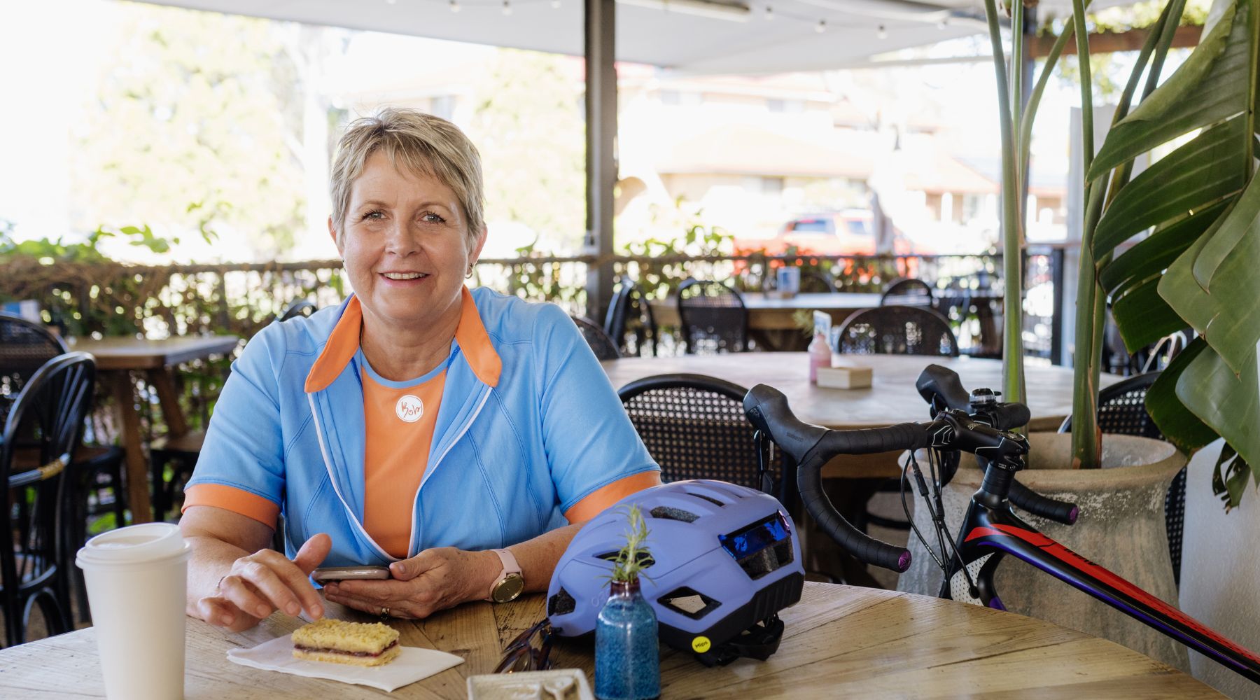 female cyclist in a blue jersey sitting in a coffe shop