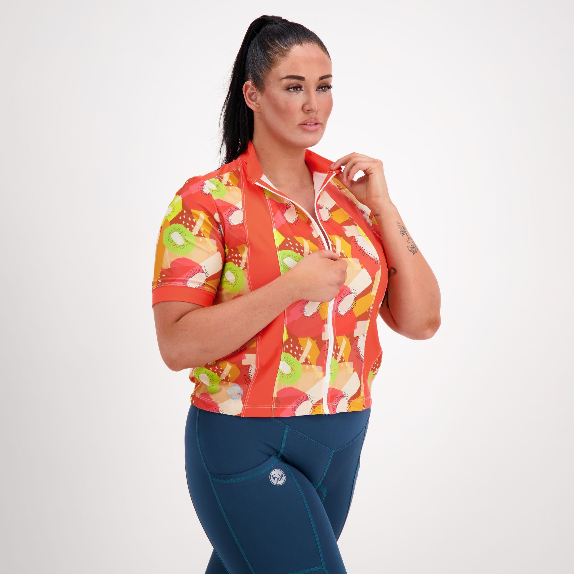 Front side view of model wearing Carefree Cycling Jersey in Tutti Fruity orange print