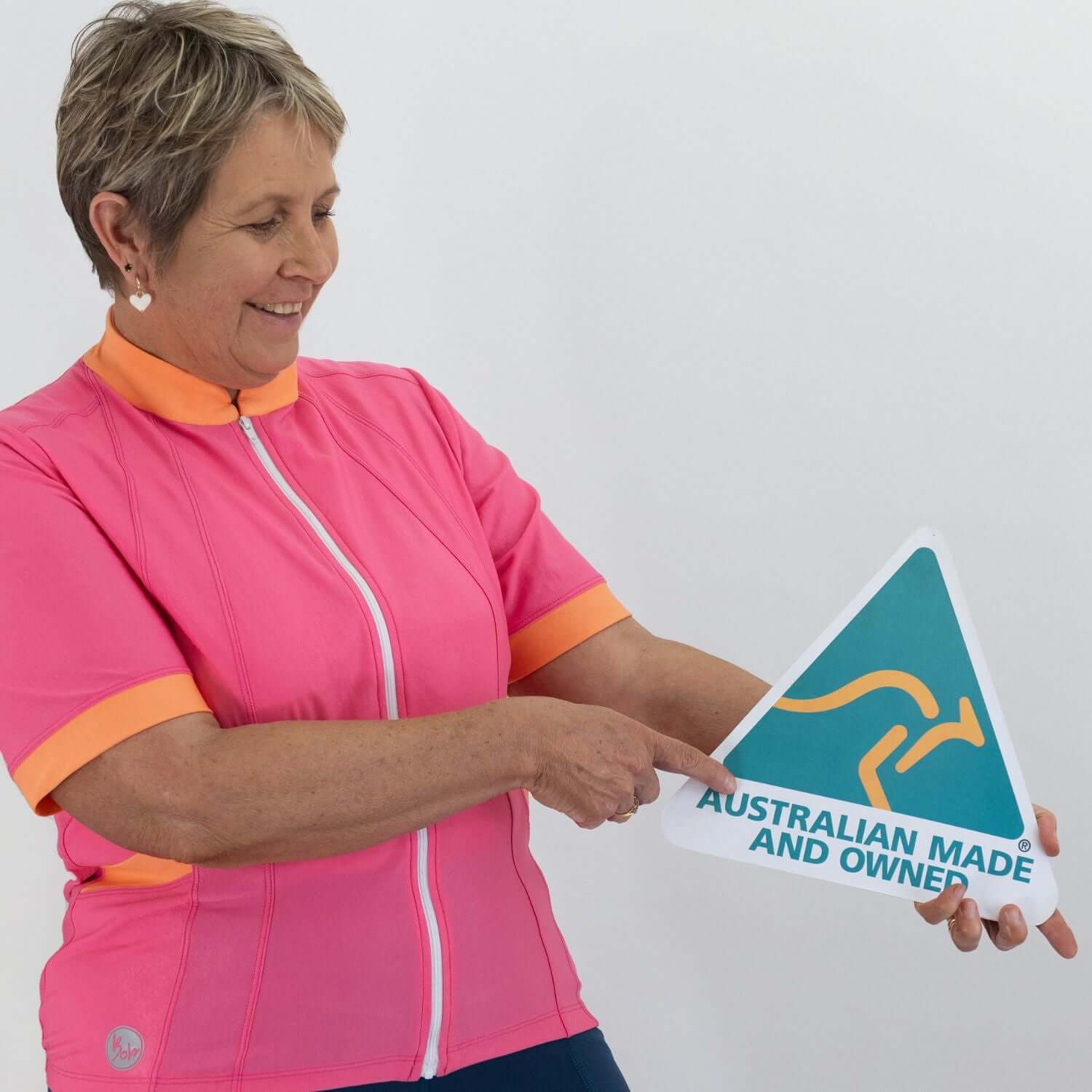 Woman in pink and orange cycling outfit holding an 'Australian Made and Owned' sign.