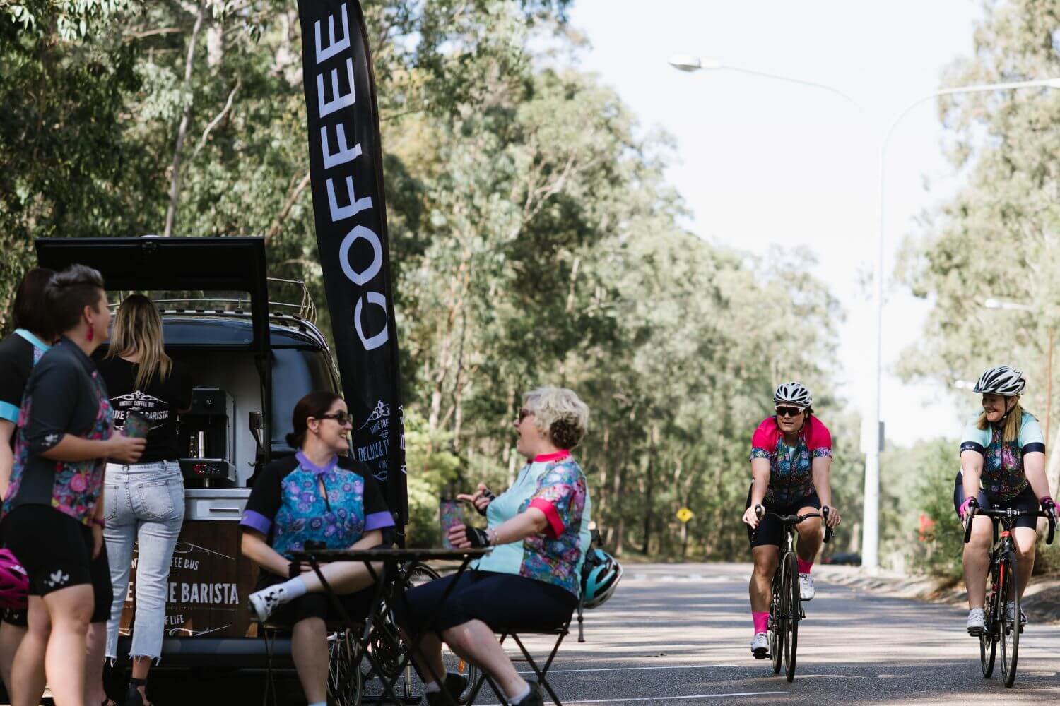 Cyclists and a coffee truck on a road with trees in the background