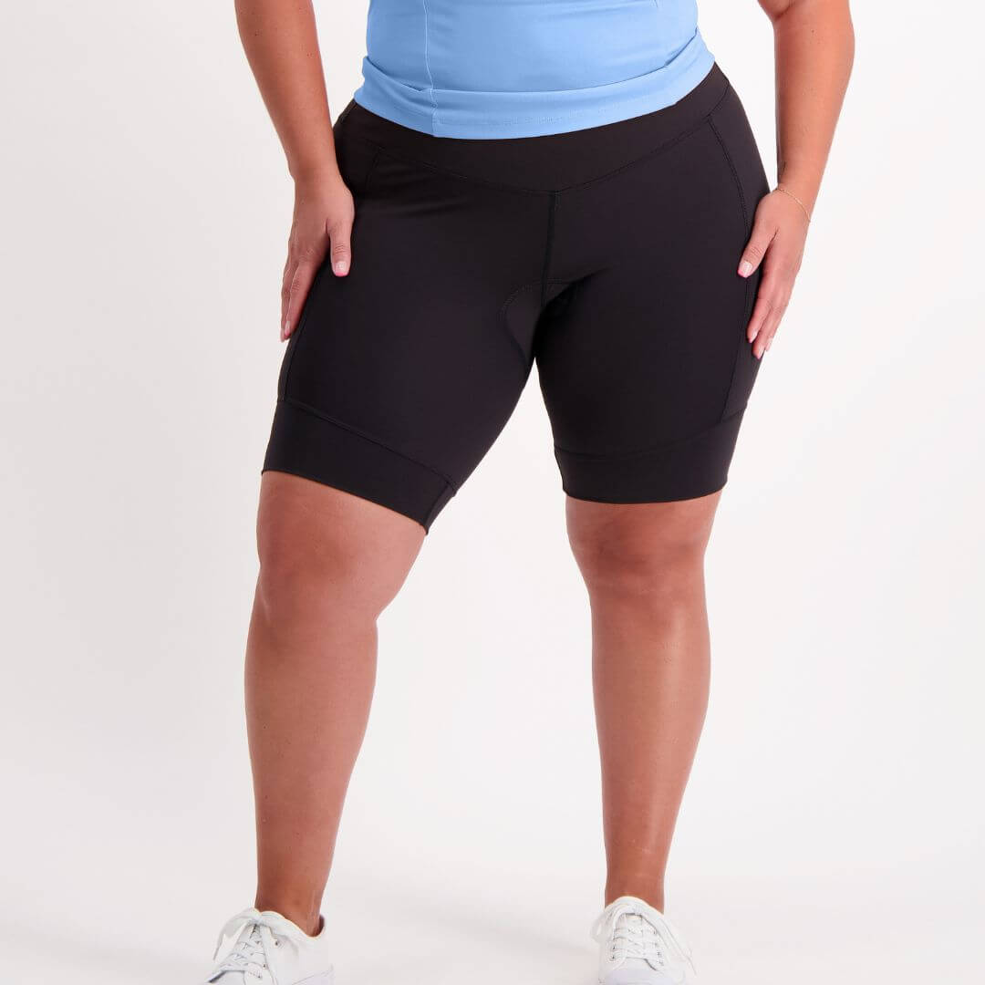 Person wearing black padded bike shorts and a light blue top on a white background