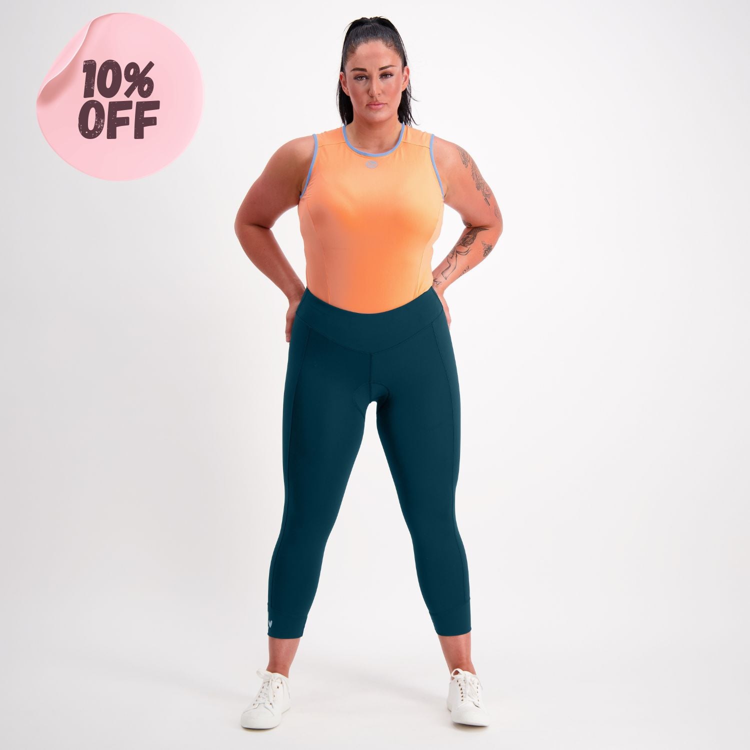 cyclist wearing an orange base layer and capri padded cycling pants