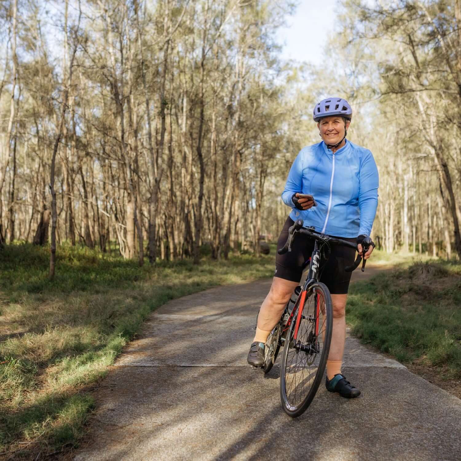 Woman riding a bicycle on a path surrounded by trees