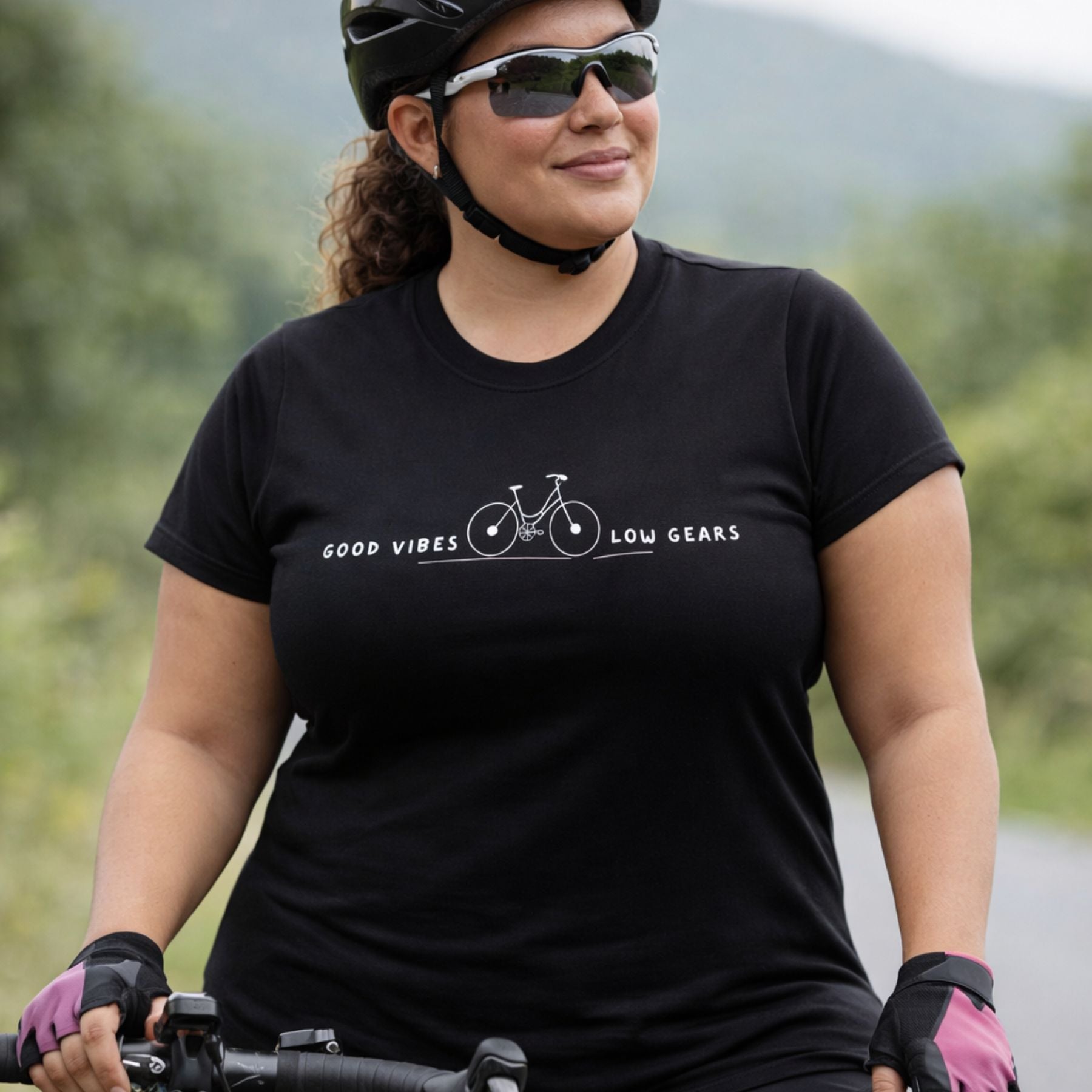 Person wearing a black t-shirt with a bicycle graphic and text, standing outdoors on a road.