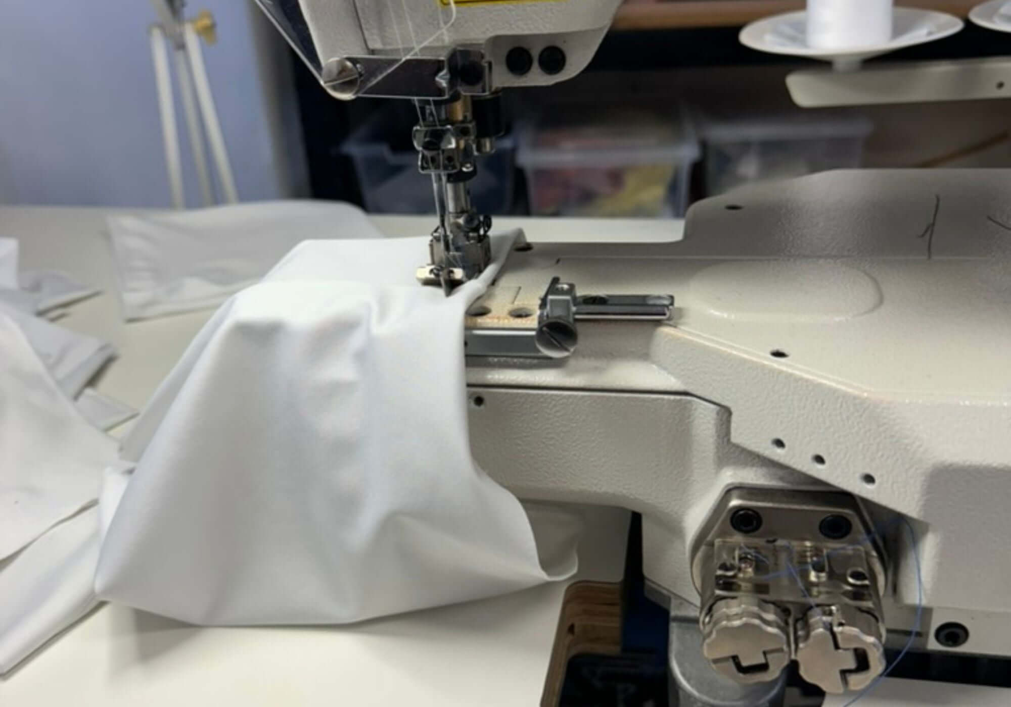 Sewing machine stitching white fabric with a blurred background