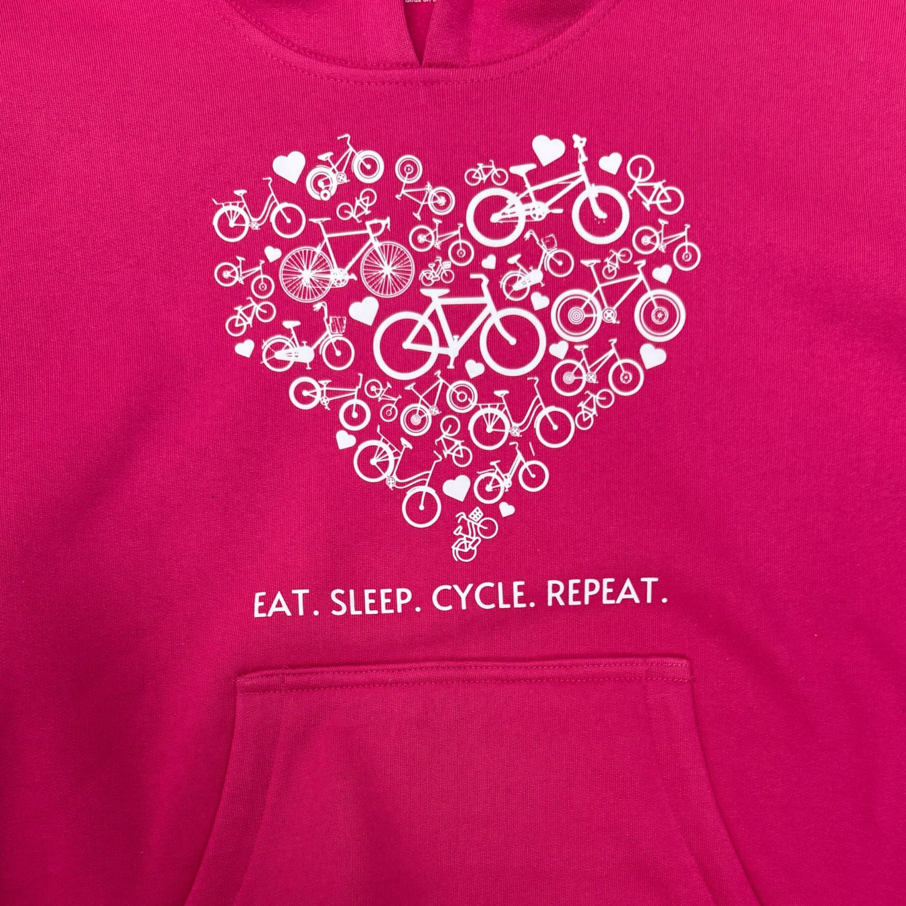 Detailed view of white graphic on pink hoodie—tiny bicycles forming a heart