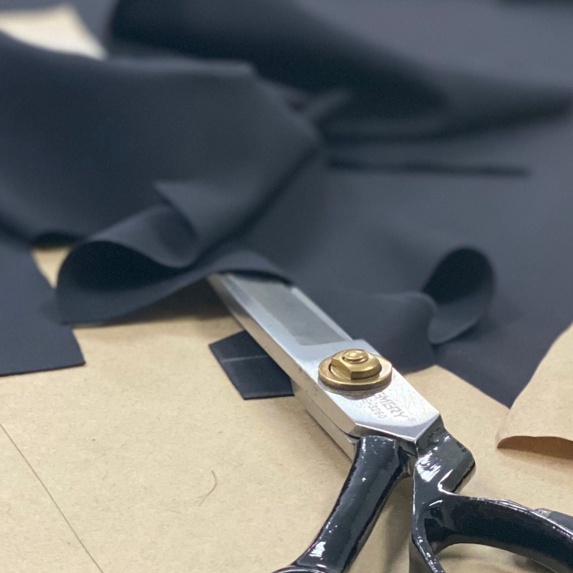 A pair of black handled sewing scissirs on some patterns with fabric