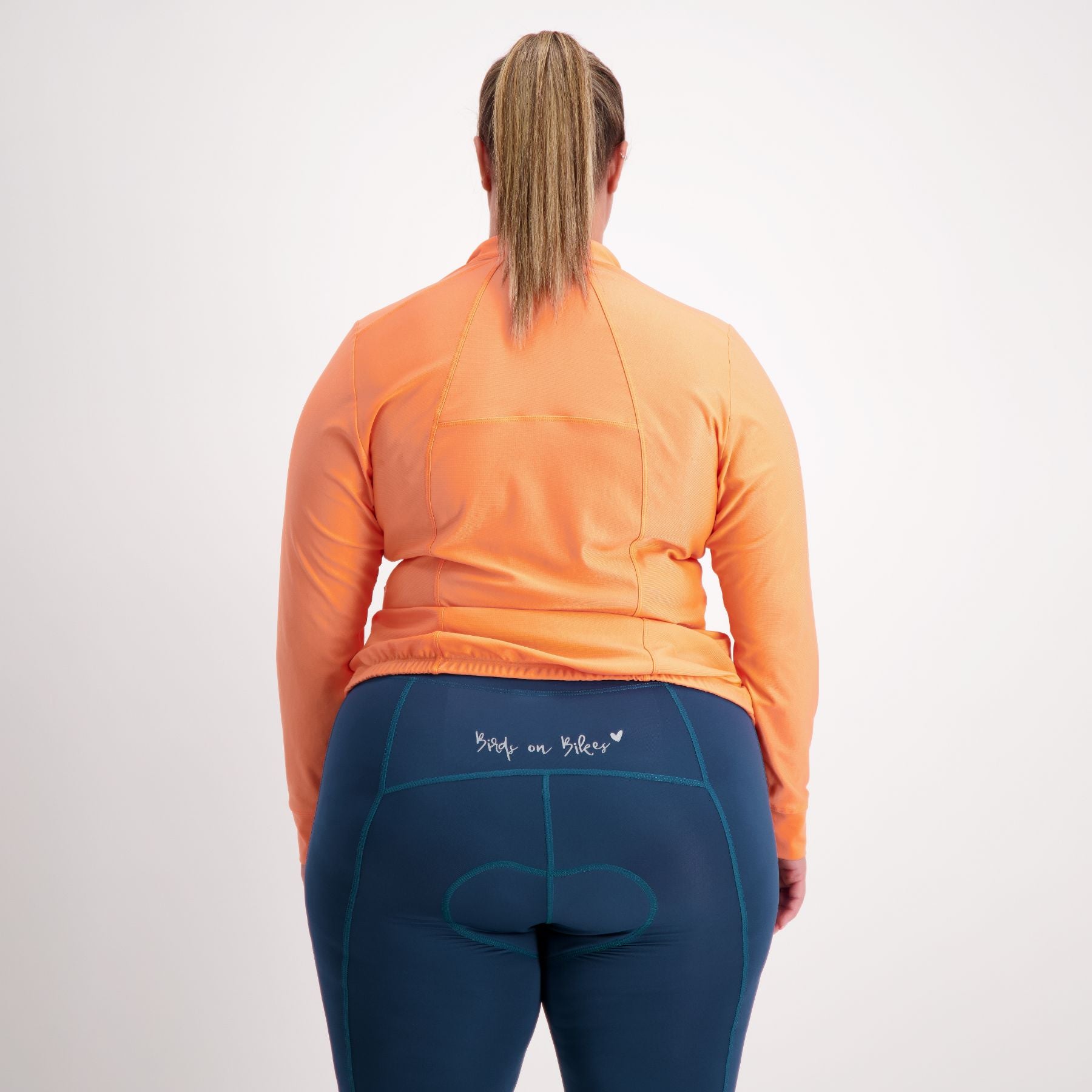 back view of Female cyclist in orange Long sleeve cycling jersey 
