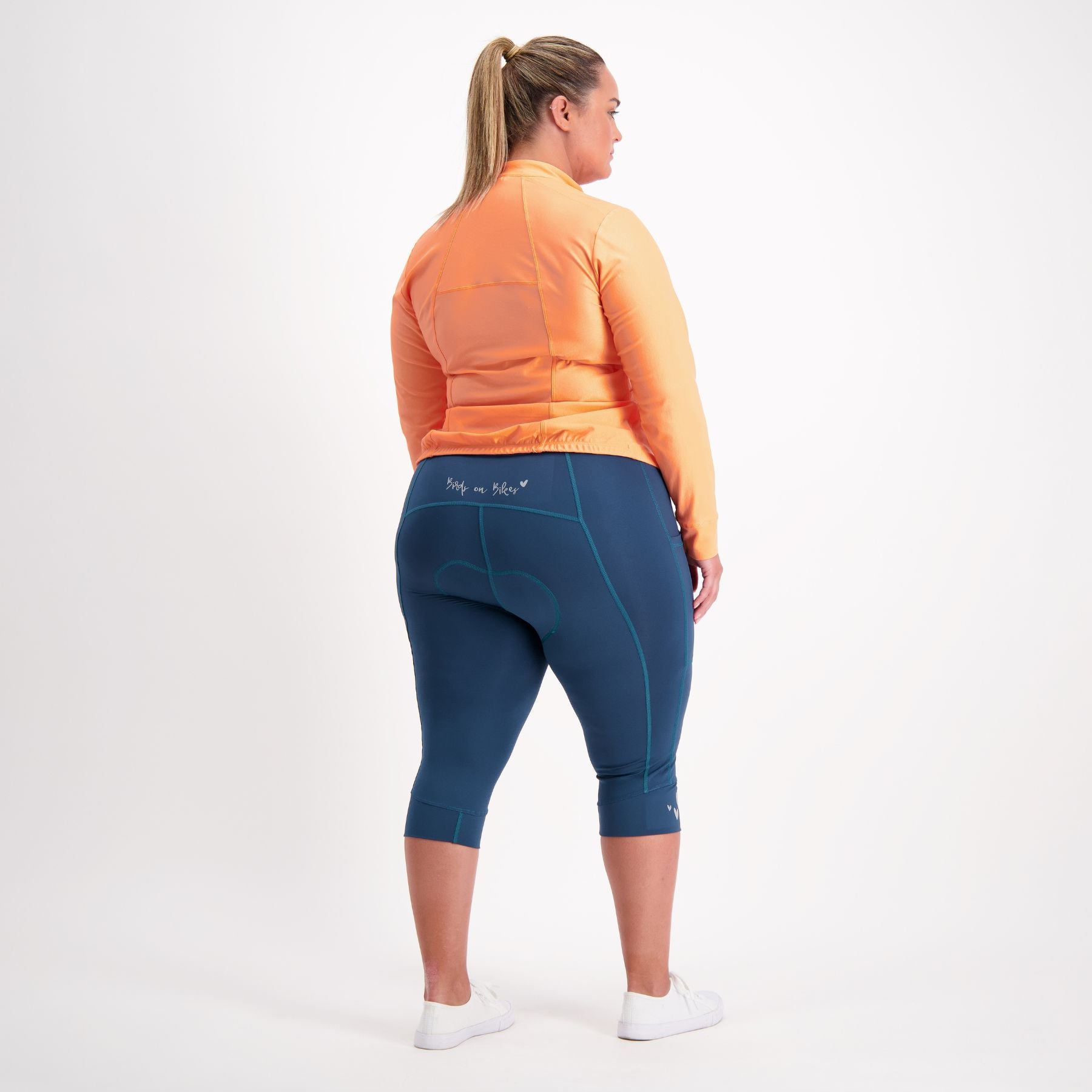 full body view of Female cyclist in orange Long sleeve cycling jersey 