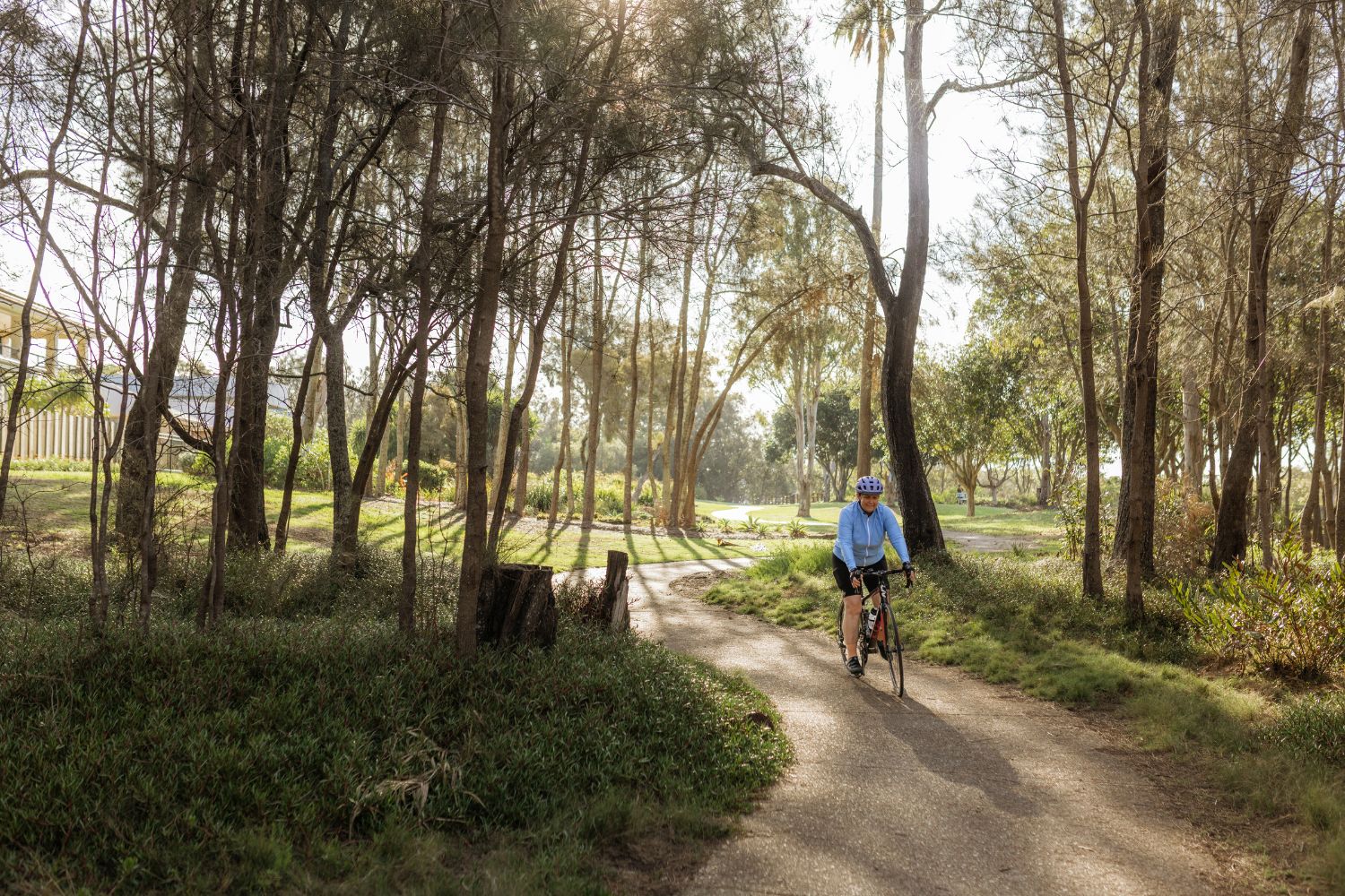 female cyclist riding along a tree lined path