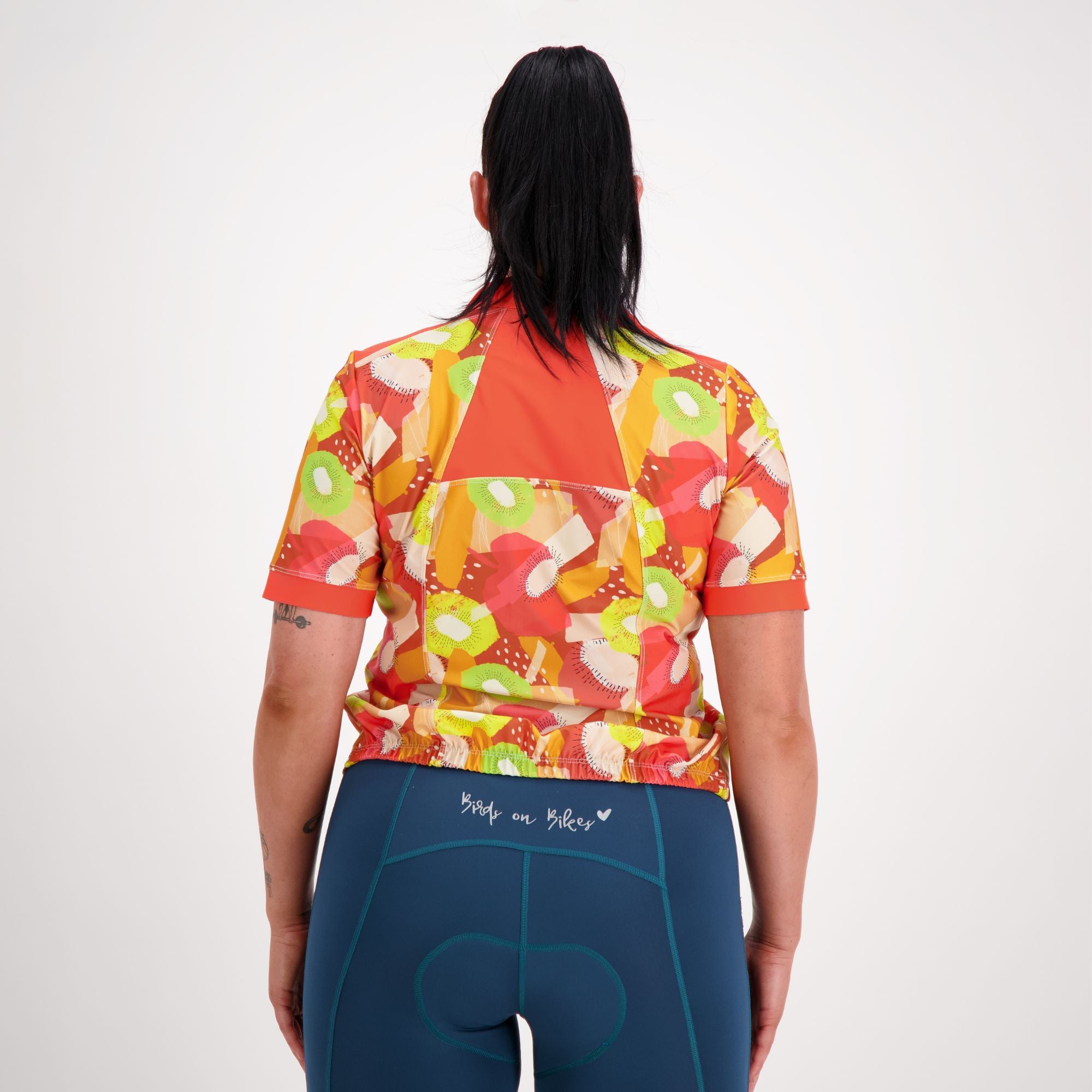 Back view of model wearing Carefree Cycling Jersey in Tutti Fruity orange print