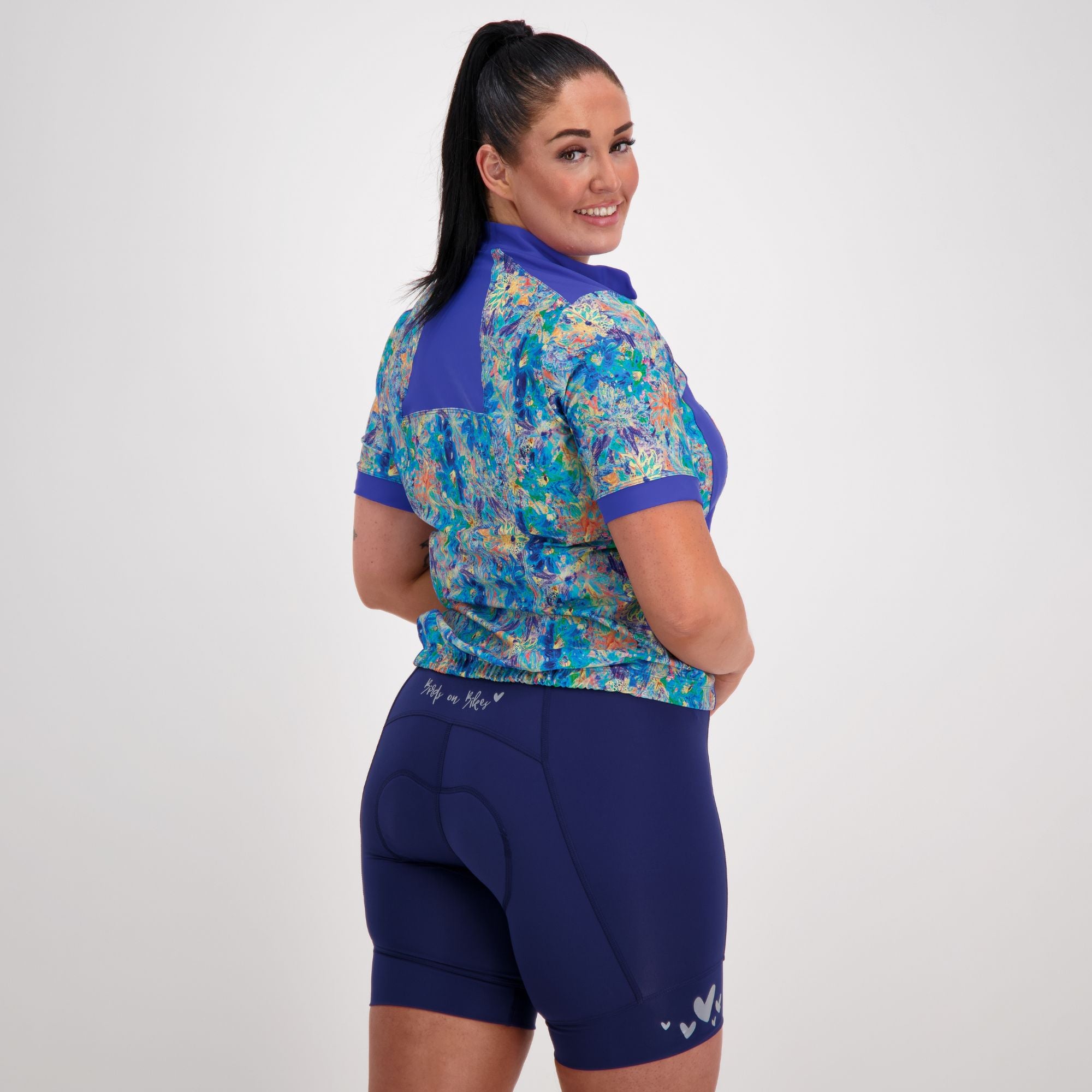 Back view of model wearing the blue artsy floral carefree cycling jersey