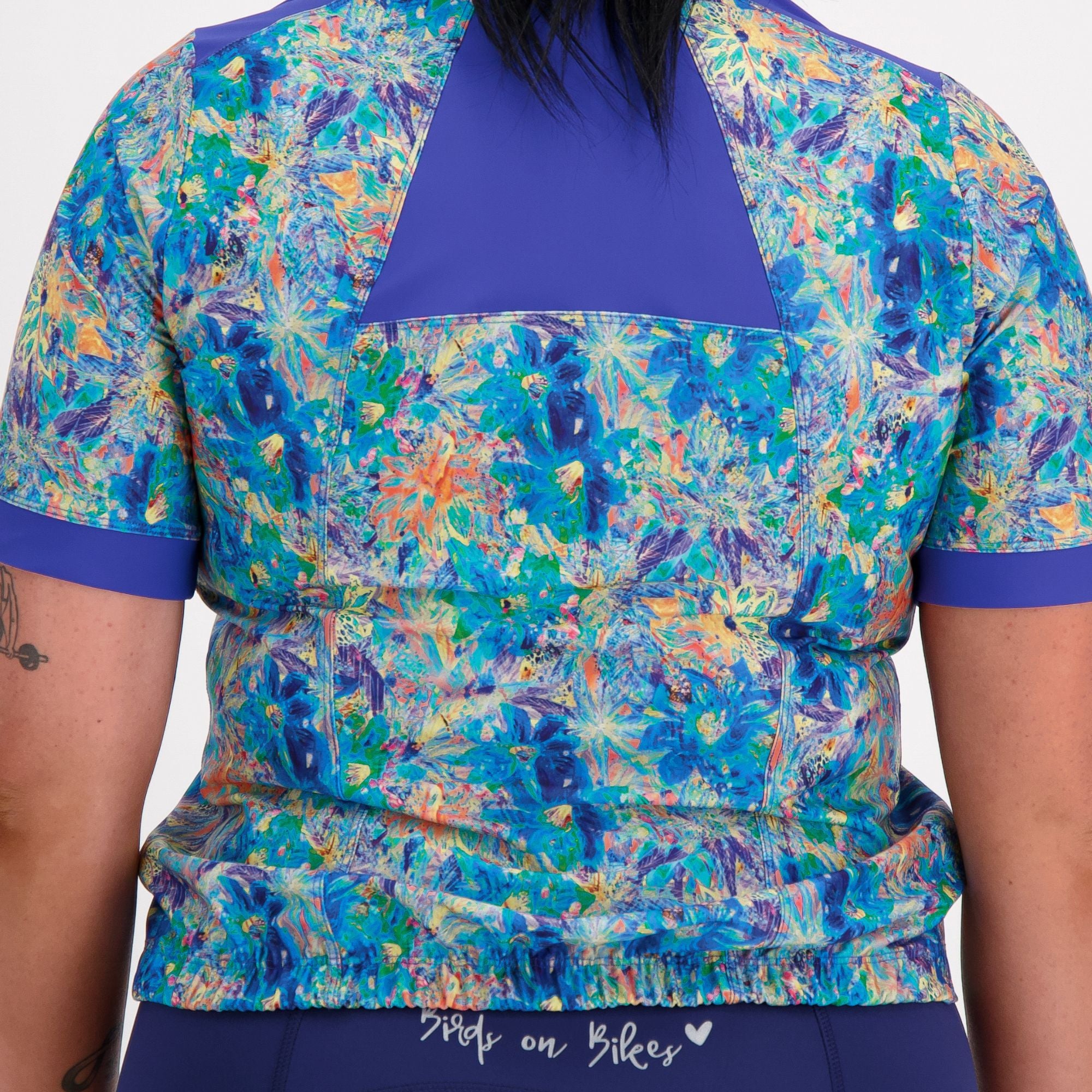 Back close up view of model wearing the blue artsy floral carefree cycling jersey