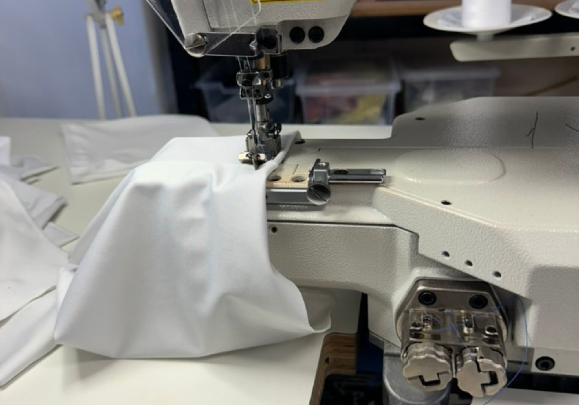 Sewing machine stitching white fabric with a blurred background