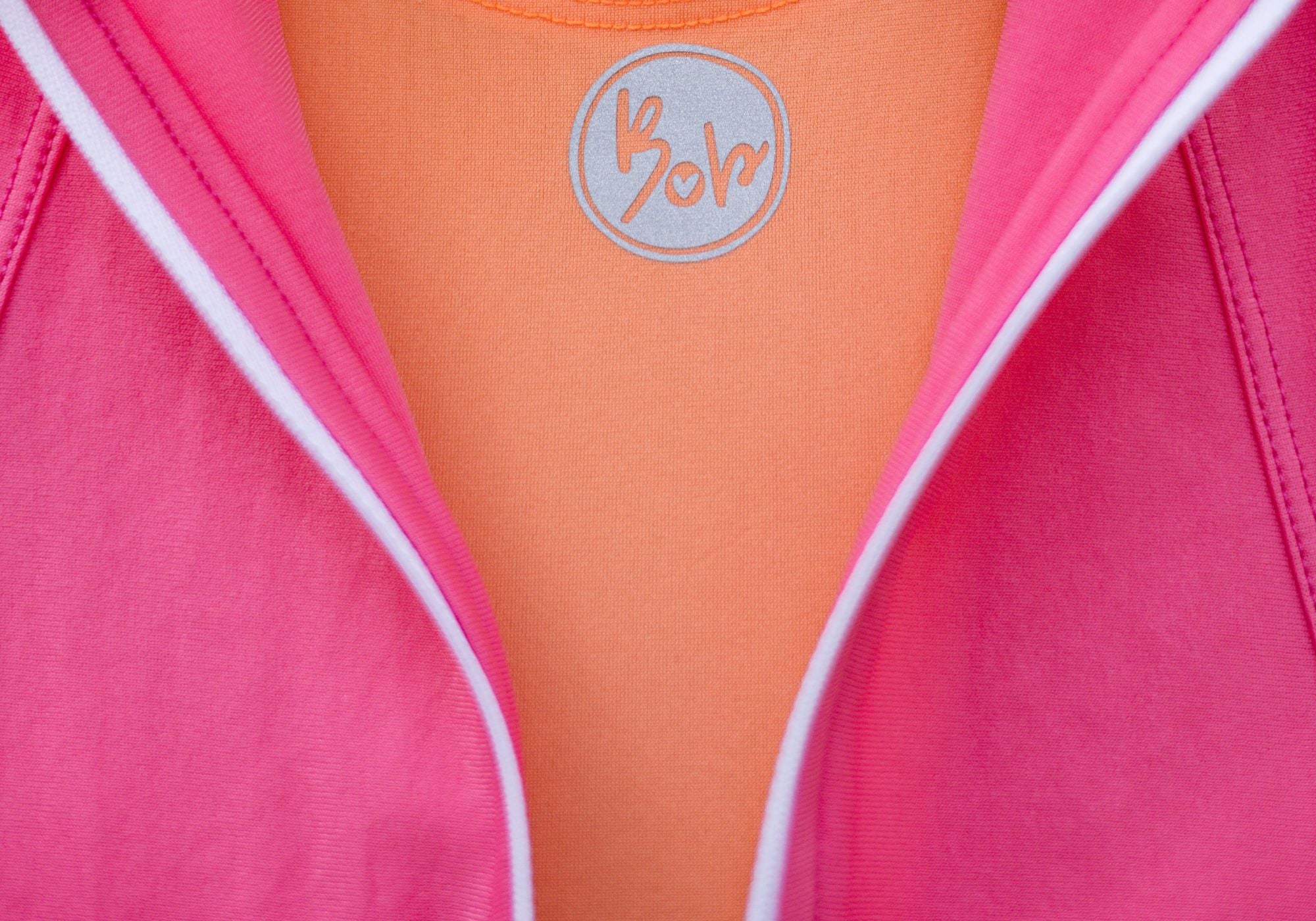 Close-up of a pink garment with a brand logo on an orange background
