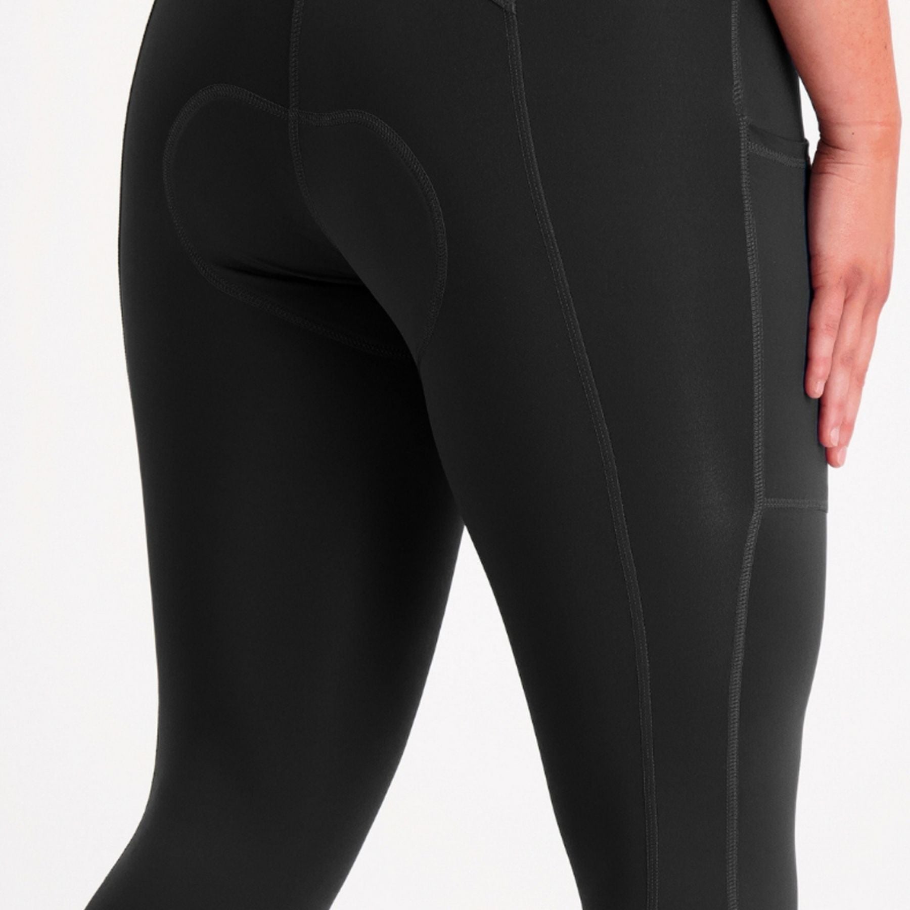 Close-up of a person wearing black high-waisted cycling tights, showing the rear cushioning and side pocket detail against a plain white background.