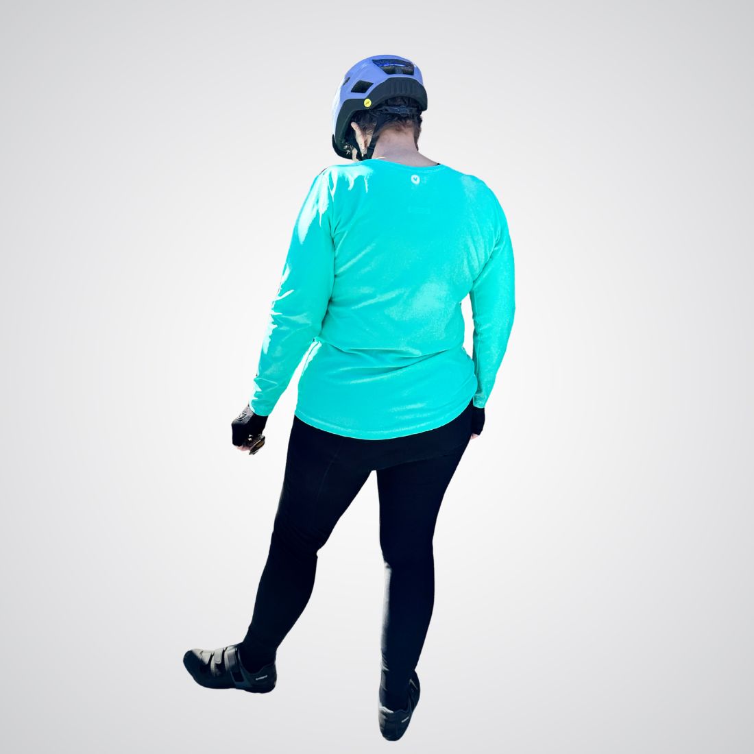 Person wearing a bright turquoise long-sleeve shirt and black pants on a white background