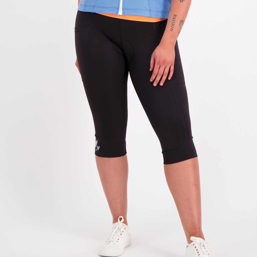 Person wearing black knee length bike pants with padding on a white background